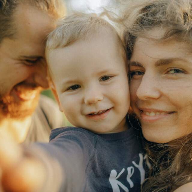 Woman holding smiling toddler outdoors in warm sunlight