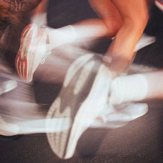 Gros plan sur les pieds d'un coureur portant des chaussures de sport blanches et rouges sur un tapis roulant