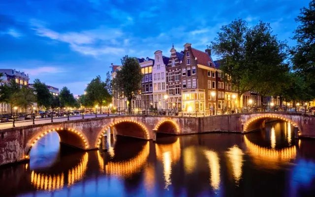 Amsterdamer Grachten mit beleuchteten Brücken und Häusern in der Abenddämmerung