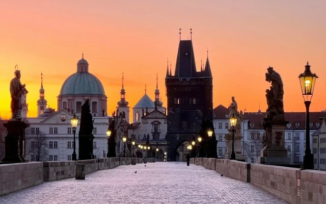 Charles-Brücke in Prag bei Sonnenaufgang mit beleuchteten Statuen und gotischen Türmen