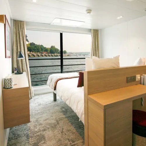 Cabine de navire de croisière avec lit, hublot donnant sur l'eau et décoration intérieure en bois clair