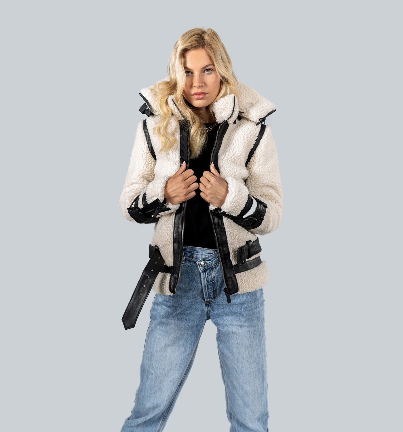 Blondes Mädchen trägt Creme-Wollvlies-Jacke mit schwarzen Lederelementen über Jeans