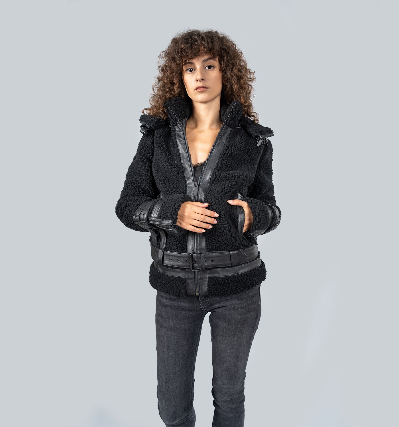Mädchen mit lockigen Haaren in schwarzer Lederjacke mit Kragen steht frontal zur Kamera