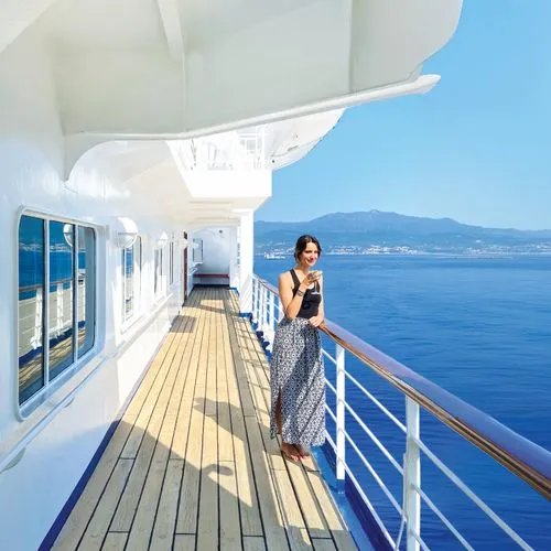 Femme en robe debout sur le pont d'un navire de croisière avec vue sur la mer méditerranée et les montagnes