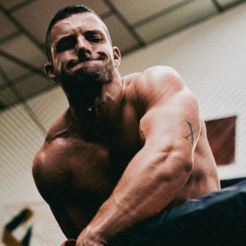 Homme musclé torse nu fléchissant ses biceps dans un environnement intérieur