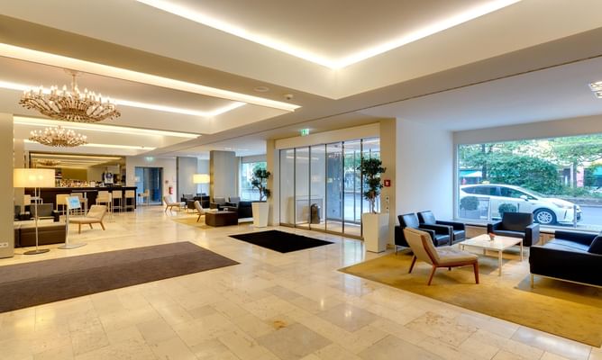 Modernes helles Hotelfoyer mit Marmorboden, Designer-Möbeln, indirekter Deckenbeleuchtung und großen Fenstern
