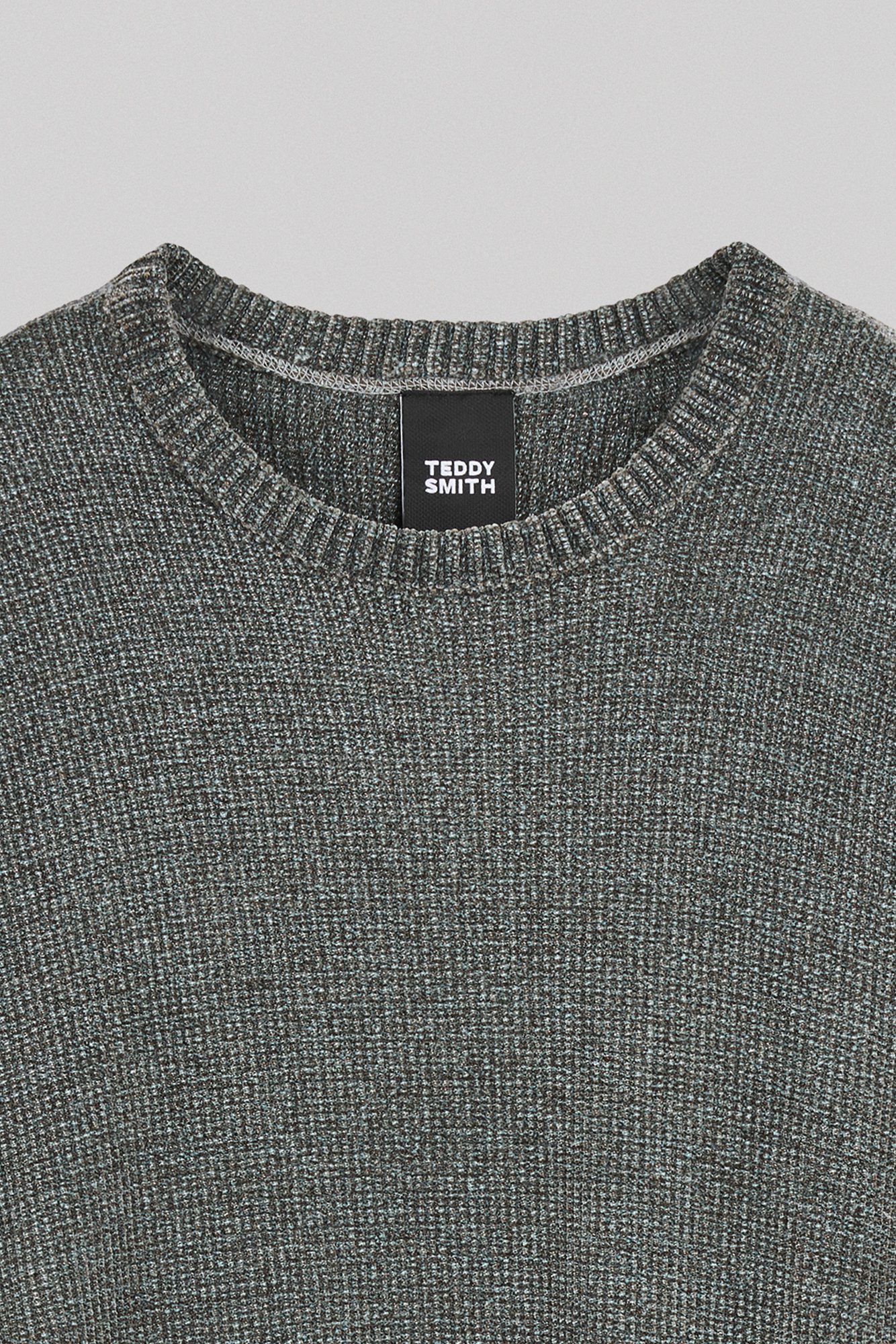 Détail du col rond et de l'étiquette de marque sur pull gris texturé
