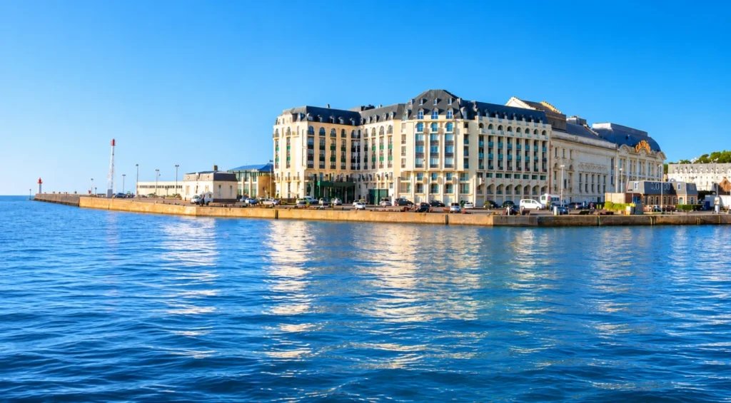Façade d'un hôtel belle époque jaune et noir au bord de l'eau avec port.