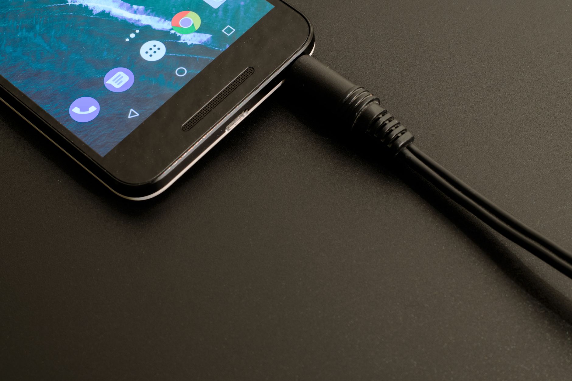 Téléphone Android avec écran coloré connecté à un câble de chargement noir tressé.